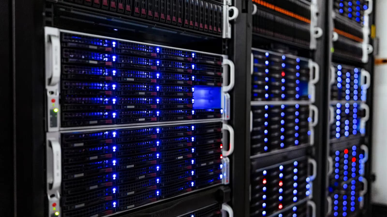 Racks de servidores com luzes LED azuis acesas em uma sala de servidores de data center