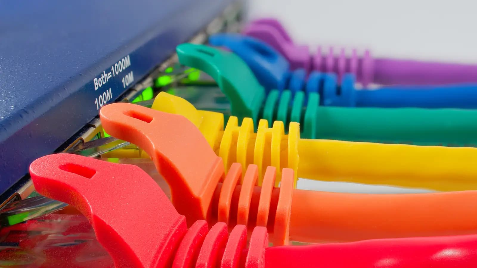 Cabos de rede coloridos conectados às portas de um switch com indicação de velocidade 10/100/1000M