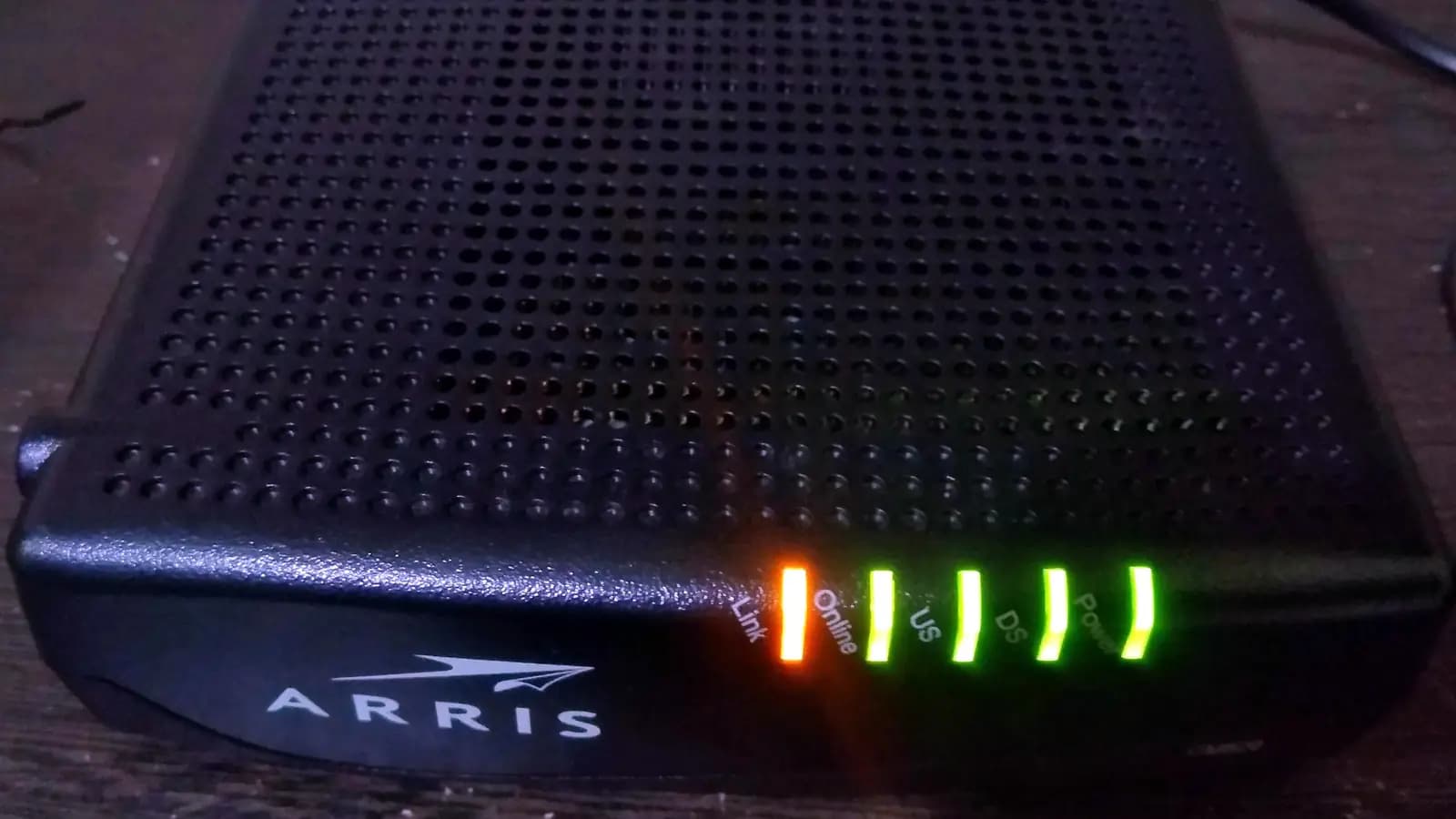 Modem a cabo preto com luzes de status acesas, uma laranja e quatro verdes