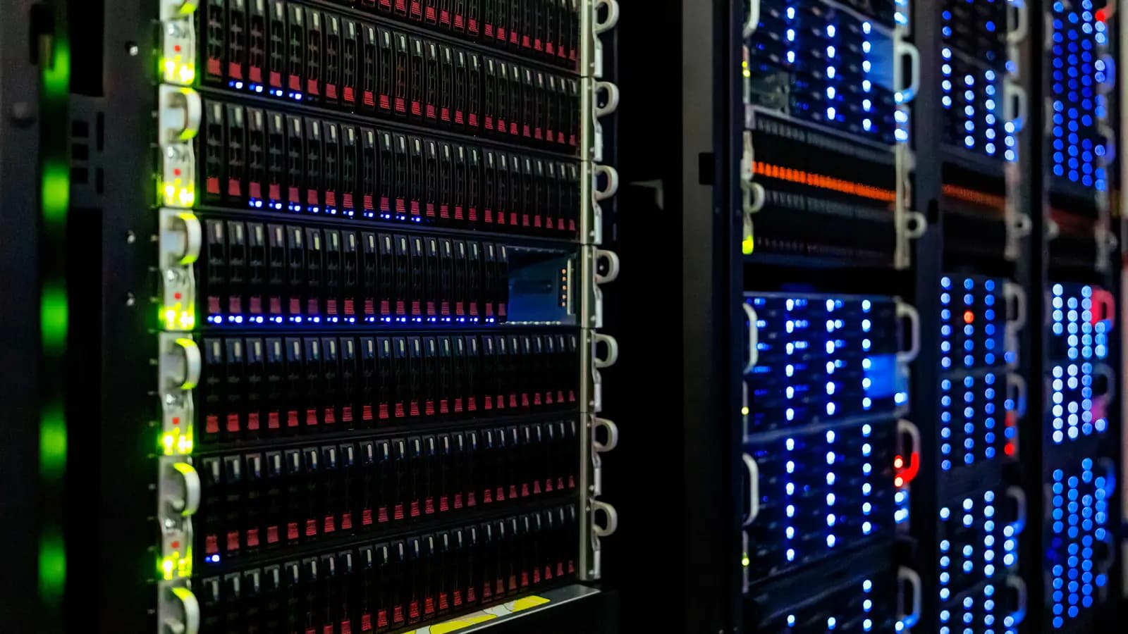Fileiras de servidores em racks com dezenas de luzes LED azuis, verdes e vermelhas acesas